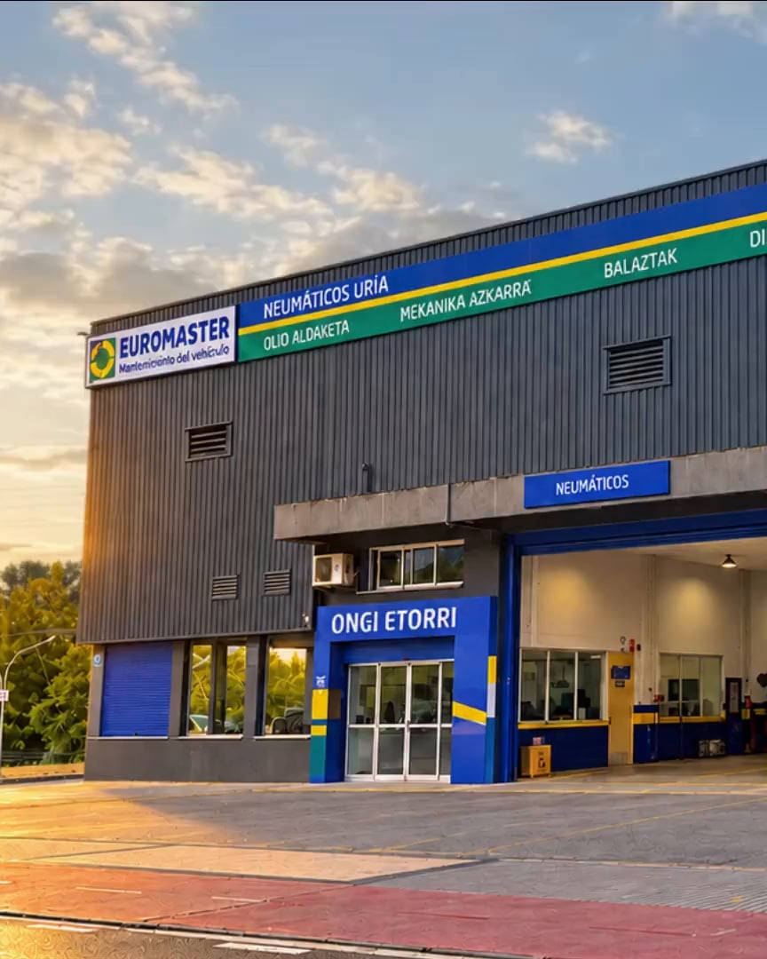 Fachada del taller Neumáticos Uría en Hernani al amanecer, con los boxes abiertos